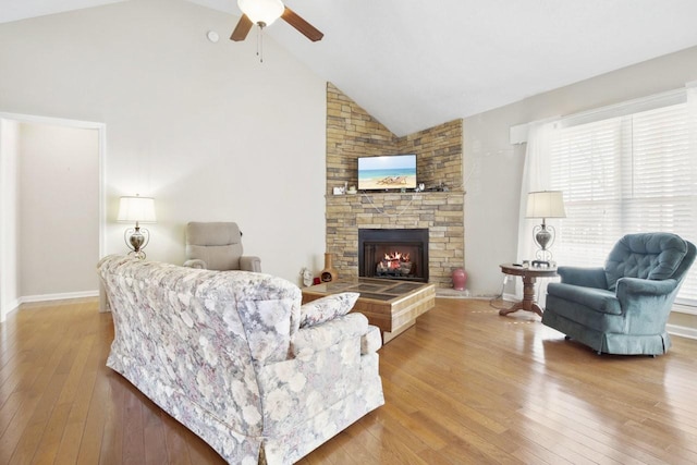 living room featuring a stone fireplace, light hardwood / wood-style flooring, and high vaulted ceiling