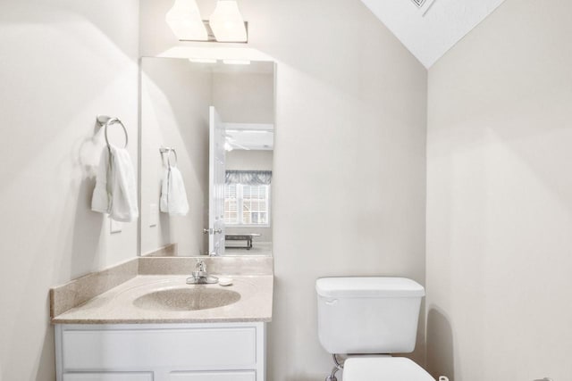 bathroom featuring vanity, lofted ceiling, and toilet