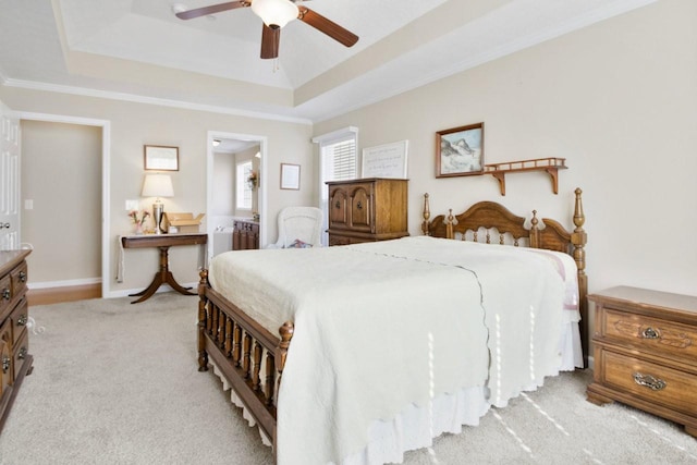 carpeted bedroom with crown molding, ceiling fan, and a tray ceiling