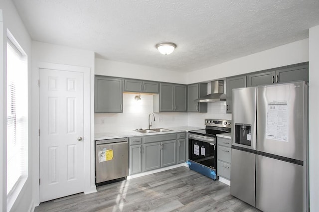 kitchen featuring wall chimney exhaust hood, appliances with stainless steel finishes, sink, and backsplash