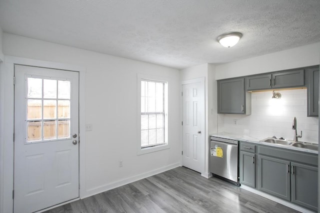 kitchen featuring sink, gray cabinetry, dark hardwood / wood-style floors, tasteful backsplash, and stainless steel dishwasher