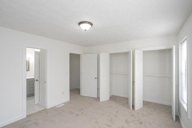 unfurnished bedroom with light carpet and connected bathroom