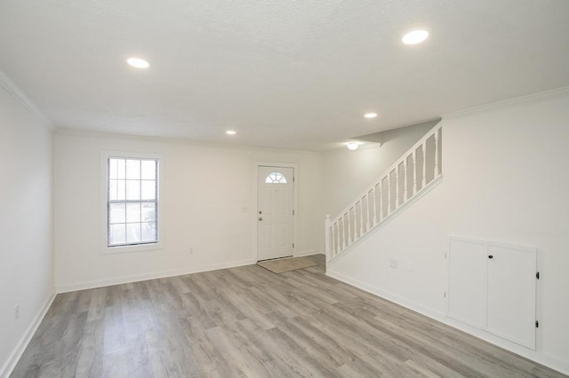 foyer with ornamental molding and light hardwood / wood-style flooring