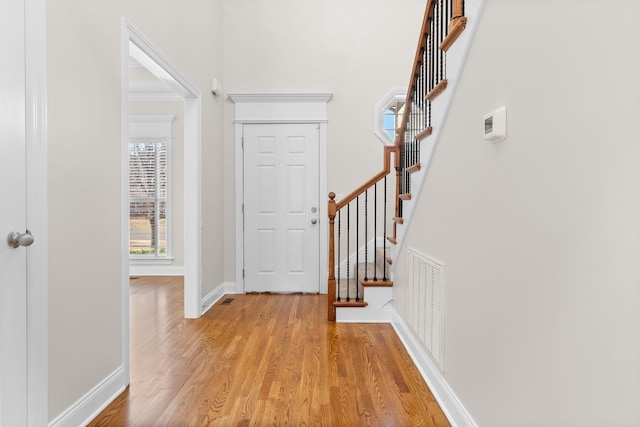 foyer with crown molding and light hardwood / wood-style flooring