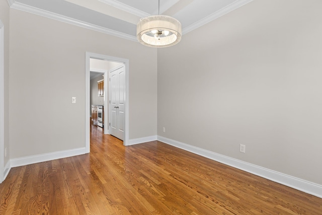 unfurnished room featuring hardwood / wood-style flooring, crown molding, and a notable chandelier