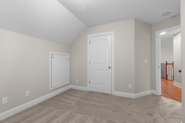 additional living space featuring vaulted ceiling and light colored carpet