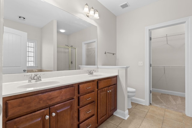 bathroom featuring tile patterned floors, toilet, a shower with door, and vanity