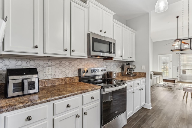 kitchen featuring decorative light fixtures, lofted ceiling, white cabinets, ceiling fan, and stainless steel appliances