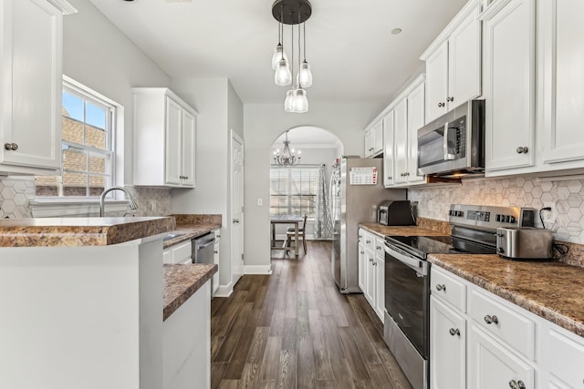 kitchen featuring appliances with stainless steel finishes, decorative light fixtures, dark hardwood / wood-style flooring, and white cabinets