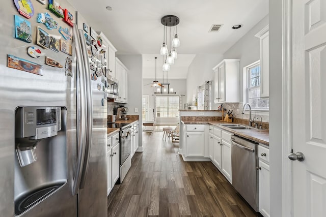 kitchen featuring sink, hanging light fixtures, kitchen peninsula, stainless steel appliances, and white cabinets