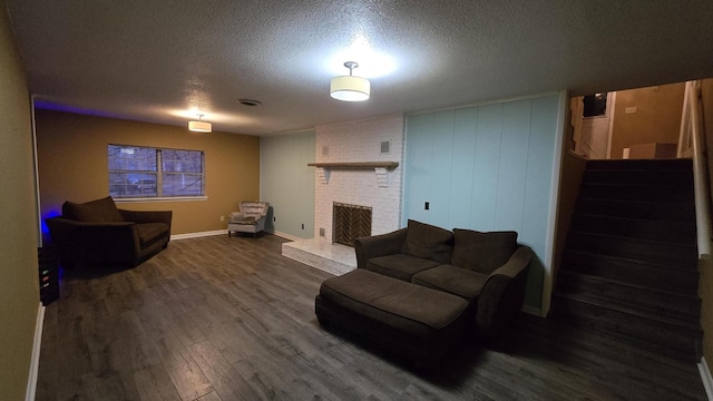 living room with a brick fireplace, hardwood / wood-style flooring, and a textured ceiling