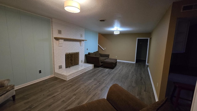 living room with dark wood-type flooring, a fireplace, and a textured ceiling
