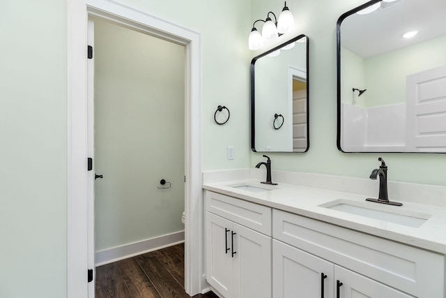 bathroom featuring toilet, hardwood / wood-style flooring, walk in shower, and vanity