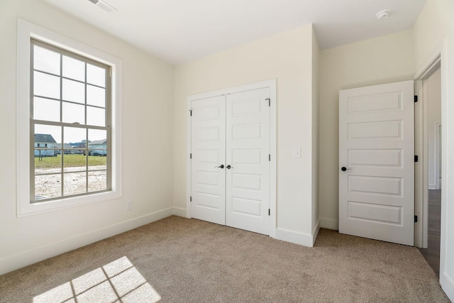 unfurnished bedroom with a closet and light colored carpet