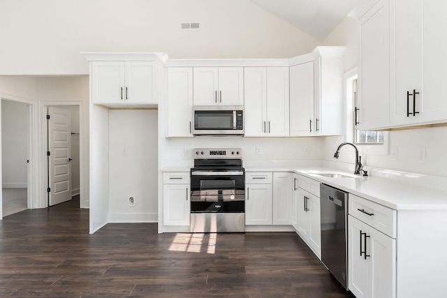 kitchen with stainless steel appliances, vaulted ceiling, dark hardwood / wood-style flooring, sink, and white cabinetry