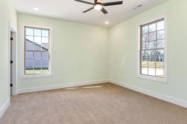 carpeted empty room with ceiling fan and a wealth of natural light