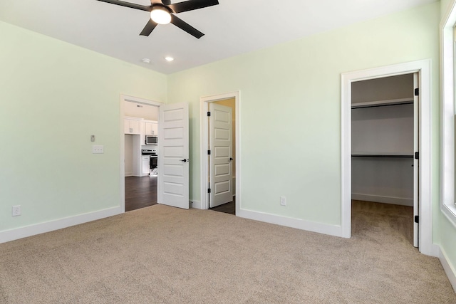 unfurnished bedroom featuring ceiling fan, carpet, a closet, and a spacious closet