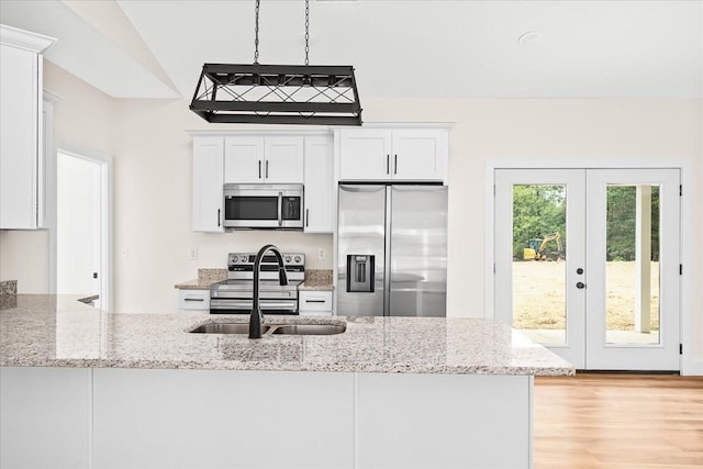 kitchen featuring pendant lighting, sink, appliances with stainless steel finishes, white cabinetry, and light stone countertops