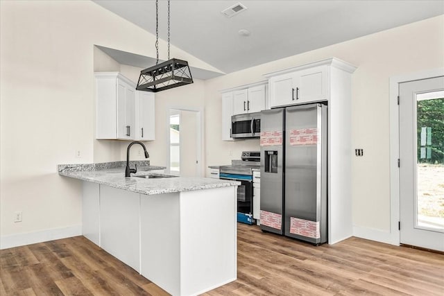 kitchen featuring lofted ceiling, sink, white cabinetry, hanging light fixtures, and appliances with stainless steel finishes