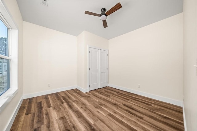 unfurnished bedroom with ceiling fan, wood-type flooring, and a closet