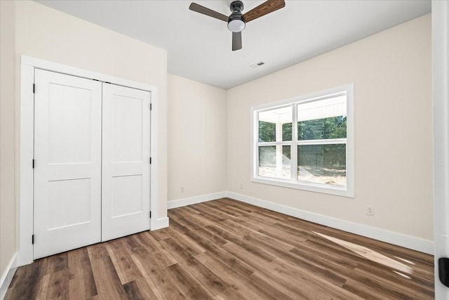 unfurnished bedroom featuring hardwood / wood-style floors, a closet, and ceiling fan