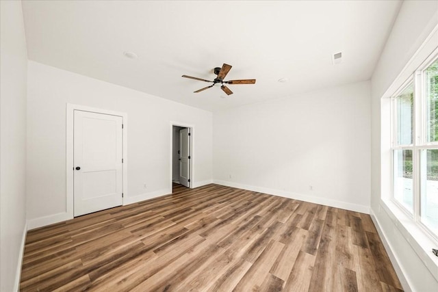 unfurnished room featuring ceiling fan, a healthy amount of sunlight, and hardwood / wood-style floors