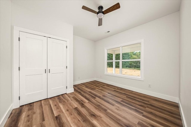 unfurnished bedroom with dark wood-type flooring, ceiling fan, and a closet