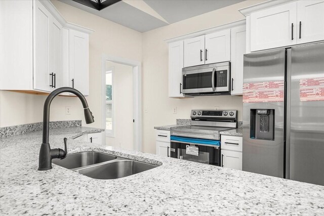 kitchen featuring white cabinetry, sink, light stone counters, and appliances with stainless steel finishes