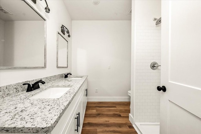 bathroom with vanity, hardwood / wood-style floors, toilet, and tiled shower