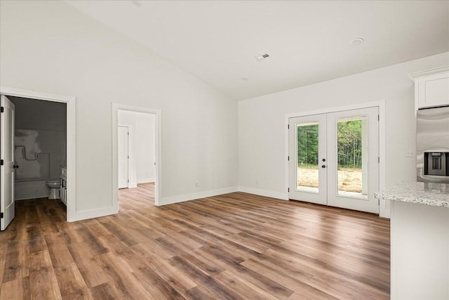 unfurnished living room featuring hardwood / wood-style floors, high vaulted ceiling, and french doors