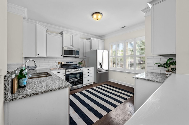 kitchen with stainless steel appliances, white cabinetry, sink, and backsplash