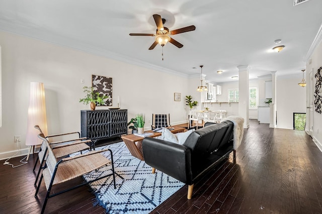 living room with crown molding, decorative columns, dark hardwood / wood-style floors, and ceiling fan