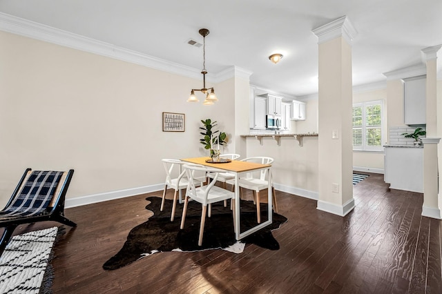 dining room with crown molding, a notable chandelier, dark hardwood / wood-style floors, and ornate columns