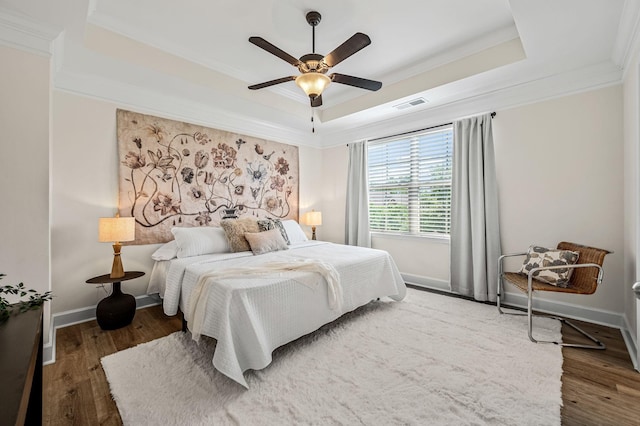 bedroom featuring crown molding, hardwood / wood-style floors, ceiling fan, and a tray ceiling