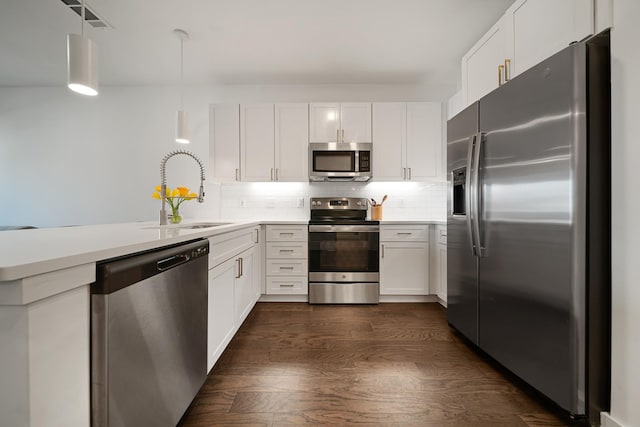 kitchen with pendant lighting, white cabinetry, sink, stainless steel appliances, and dark wood-type flooring