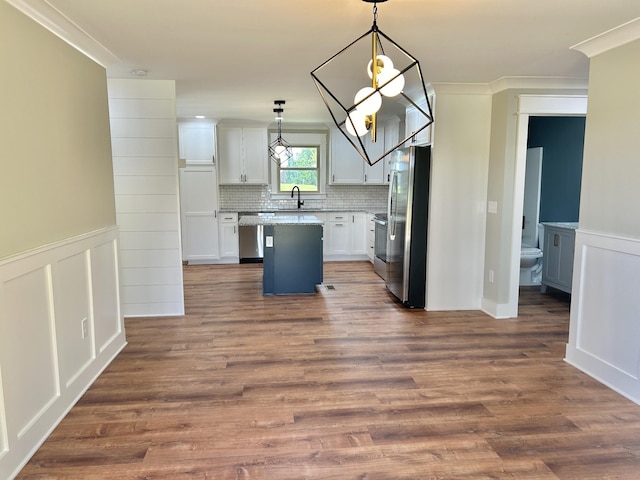 kitchen featuring sink, hanging light fixtures, appliances with stainless steel finishes, white cabinets, and backsplash