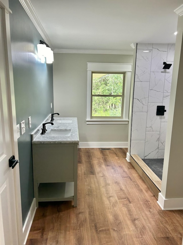 bathroom with a tile shower, vanity, ornamental molding, and hardwood / wood-style floors