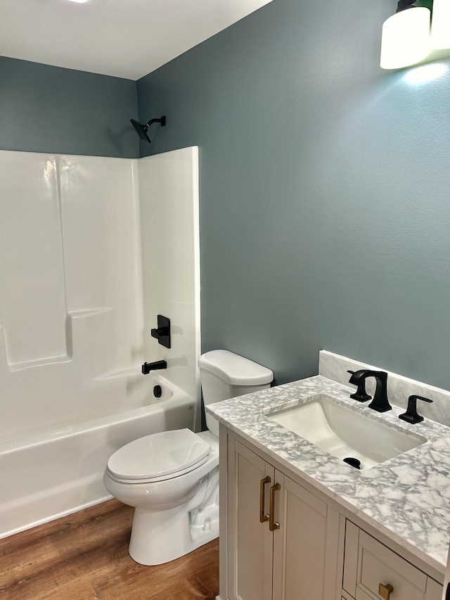 full bathroom featuring hardwood / wood-style flooring, vanity, bathing tub / shower combination, and toilet