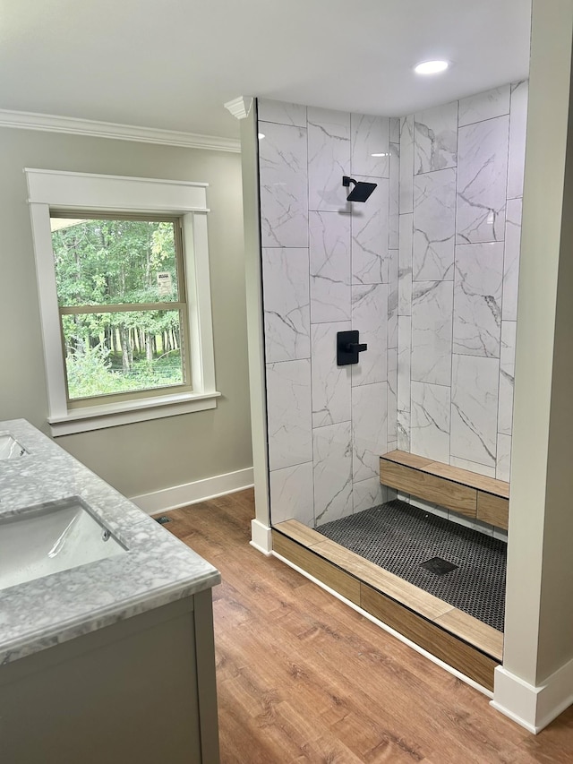 bathroom with crown molding, tiled shower, vanity, and hardwood / wood-style floors