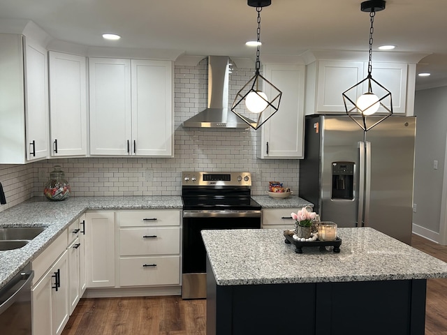 kitchen featuring white cabinetry, stainless steel appliances, decorative light fixtures, and wall chimney range hood