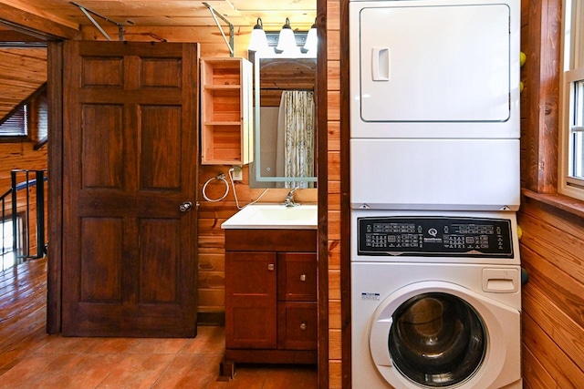 laundry area featuring stacked washer and clothes dryer, light tile patterned floors, and wood walls