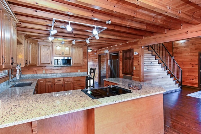 kitchen featuring beam ceiling, light stone countertops, kitchen peninsula, and appliances with stainless steel finishes