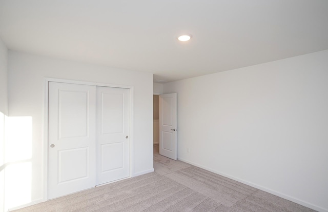 unfurnished bedroom featuring light carpet and a closet