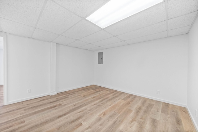 unfurnished room featuring a paneled ceiling, electric panel, and light hardwood / wood-style floors