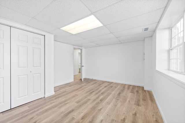 basement featuring a paneled ceiling and light wood-type flooring