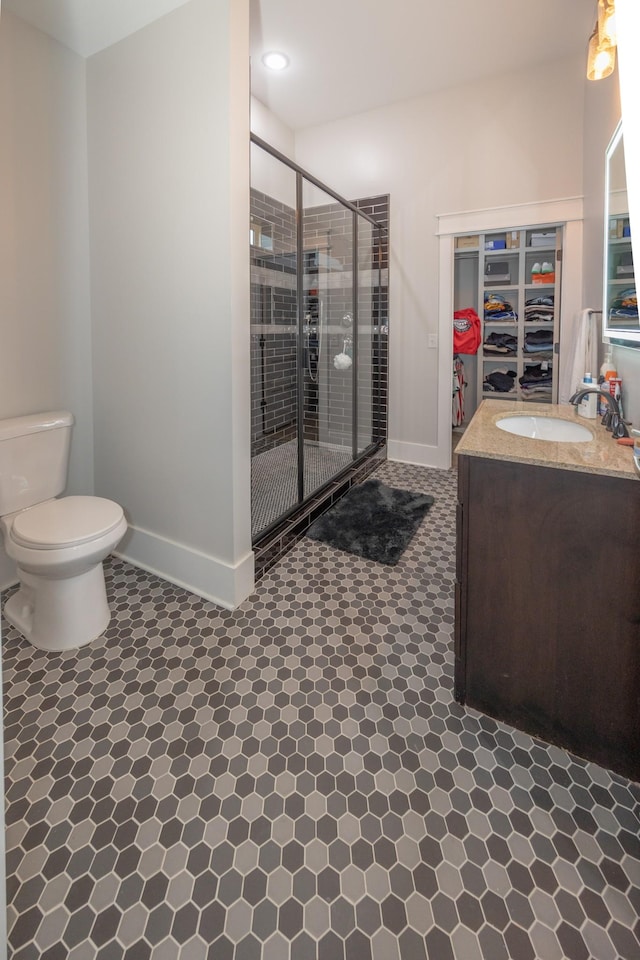 bathroom featuring a shower with door, vanity, and toilet