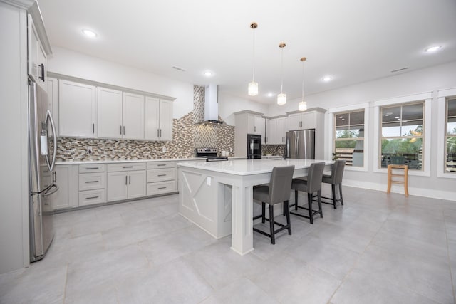 kitchen with wall chimney exhaust hood, decorative light fixtures, a center island, a kitchen breakfast bar, and stainless steel appliances