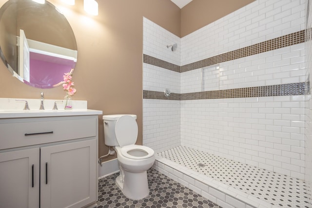 bathroom featuring tile patterned flooring, vanity, a tile shower, and toilet