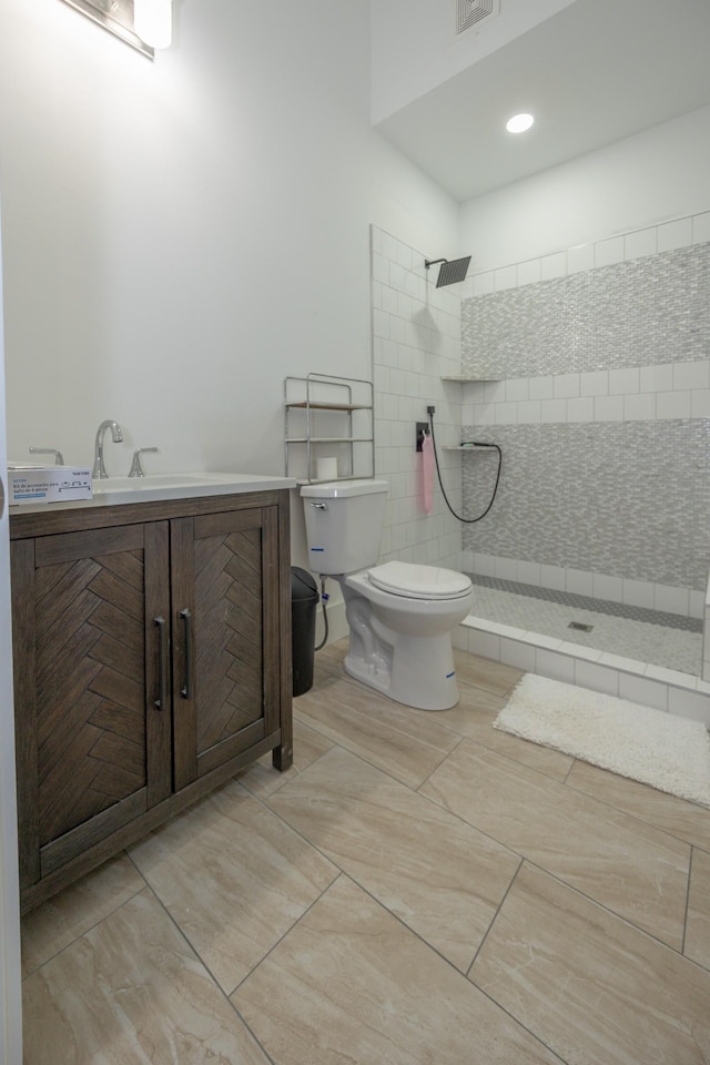 bathroom with vanity, tile patterned flooring, toilet, and tiled shower