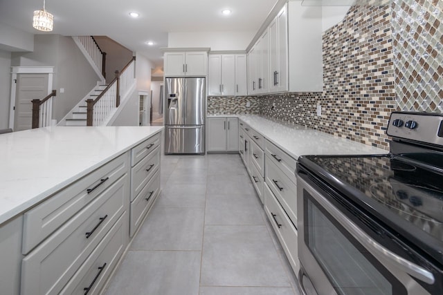 kitchen featuring white cabinetry, light tile patterned floors, appliances with stainless steel finishes, pendant lighting, and decorative backsplash